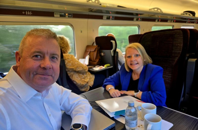 A man with a white shirt on, and a woman with a blue jacket on sat on a train.